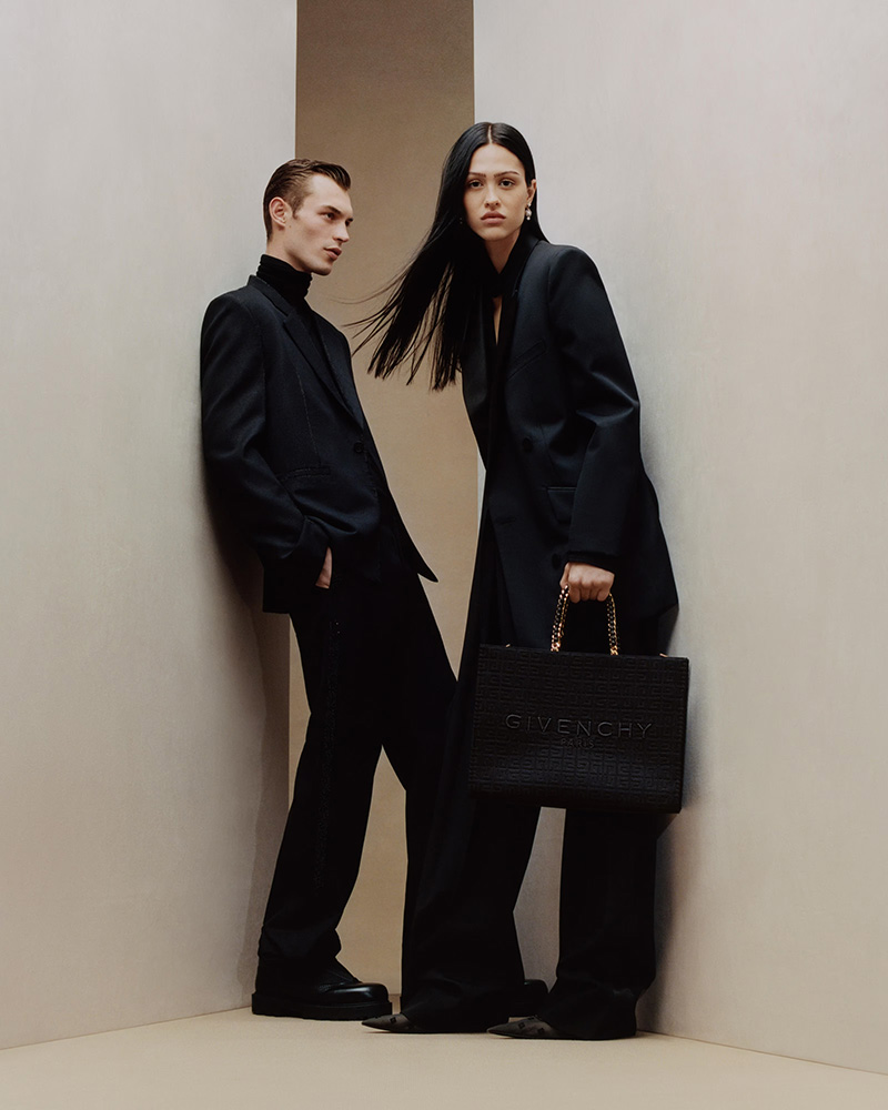 A chic and dynamic pose from Kit Butler alongside Amelia Gray, both draped in oversized black suits for the Givenchy holiday 2023 campaign.