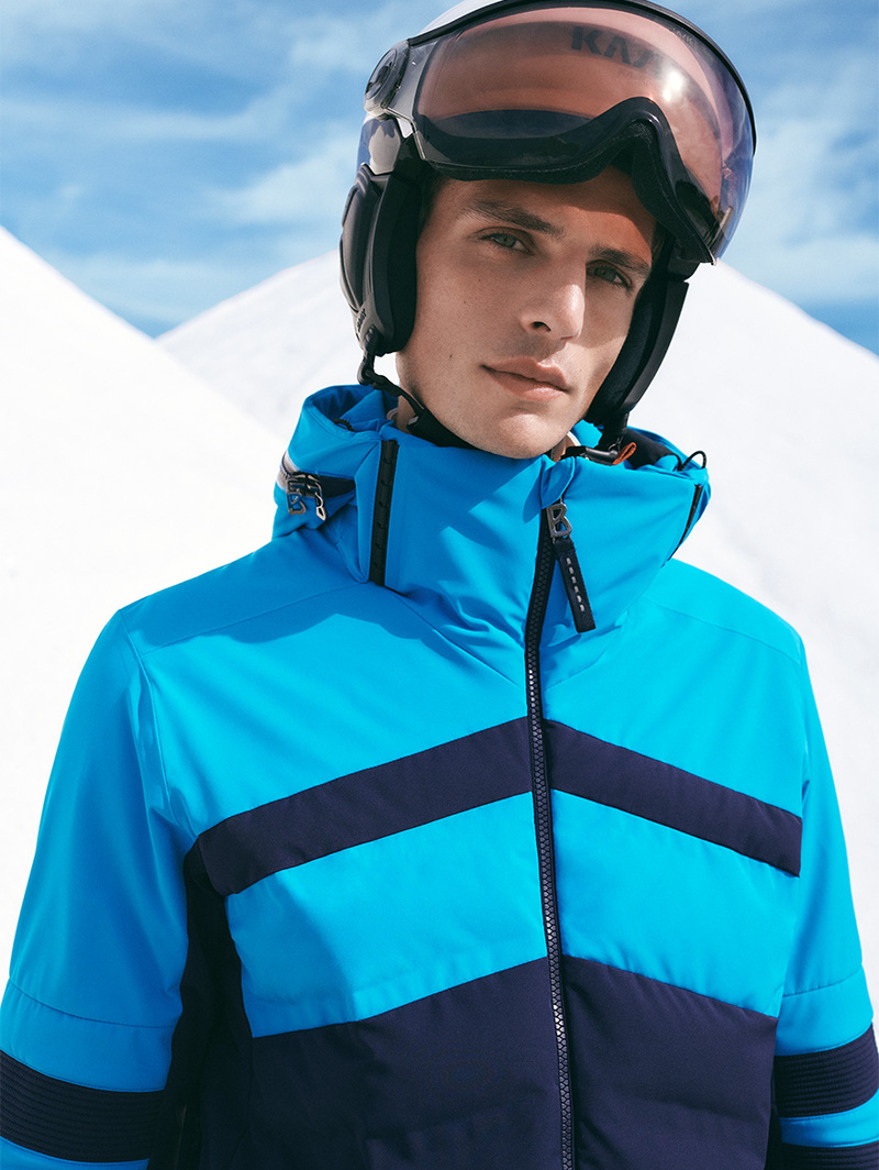 Pau Ramis dons a striking blue Bogner ski jacket with bold stripes, complemented by a sleek helmet and goggles. 