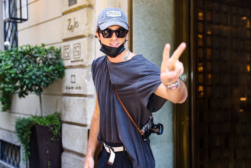 Jacob Elordi captures the laid-back essence of street style during Milan Men's Fashion Week Spring/Summer 2024, sporting an oversized tee with a relaxed cap and sunglasses.