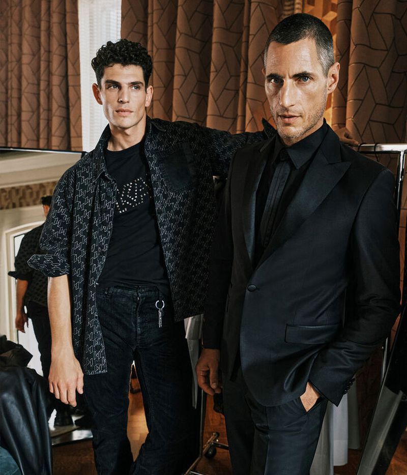 Models Pau Ramis and Axel Hermann present a juxtaposition of Karl Lagerfeld styles: Pau in a casual chic monogrammed shirt jacket and jeans and Axel in a sleek black suit.