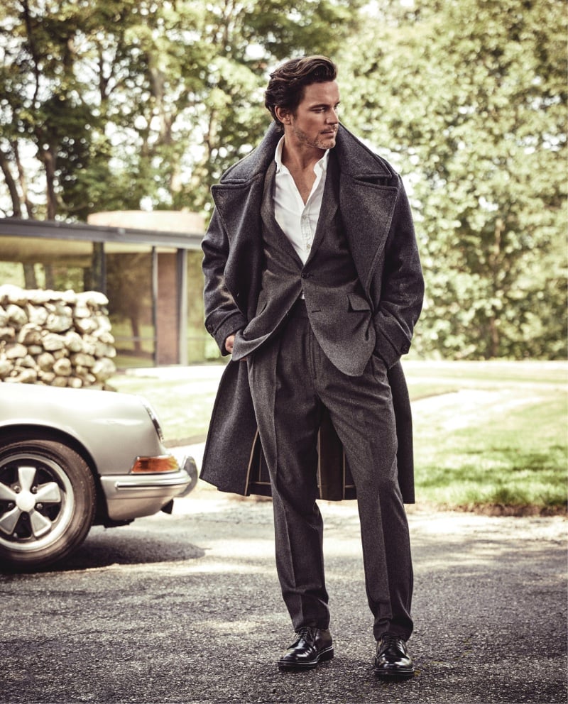 Matt Bomer strides with an air of distinction, dressed in Todd Snyder's oversized double-breasted topcoat, wool flannel suit jacket, and Gurkha trousers, finished with Alden plain toe bluchers.