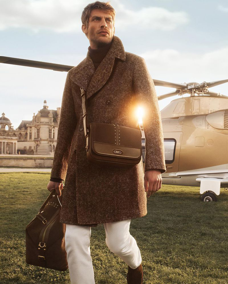Baptiste Radufe captures the essence of luxury travel with a herringbone overcoat and sleek accessories from the Michael Kors fall-winter 2023 collection.
