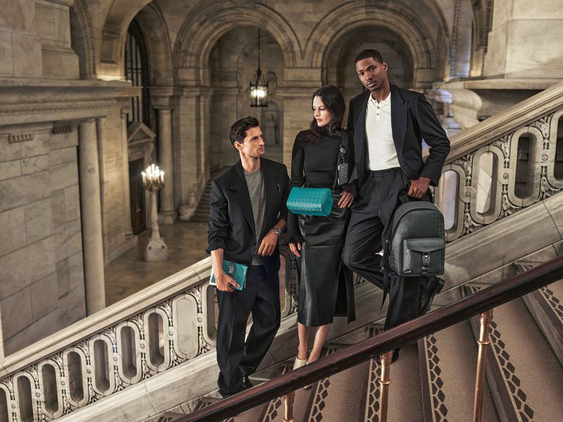 Three models ascend a grand staircase, carrying Montblanc's leather goods for the Montblanc The Library Spirit campaign. 