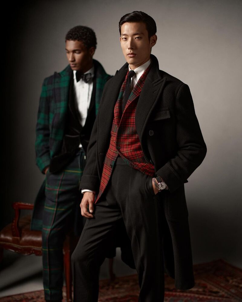 Pictured alongside Joshua Seth, Juhyung Kang commands attention in a festive look, featuring a dark overcoat and red tartan jacket. 