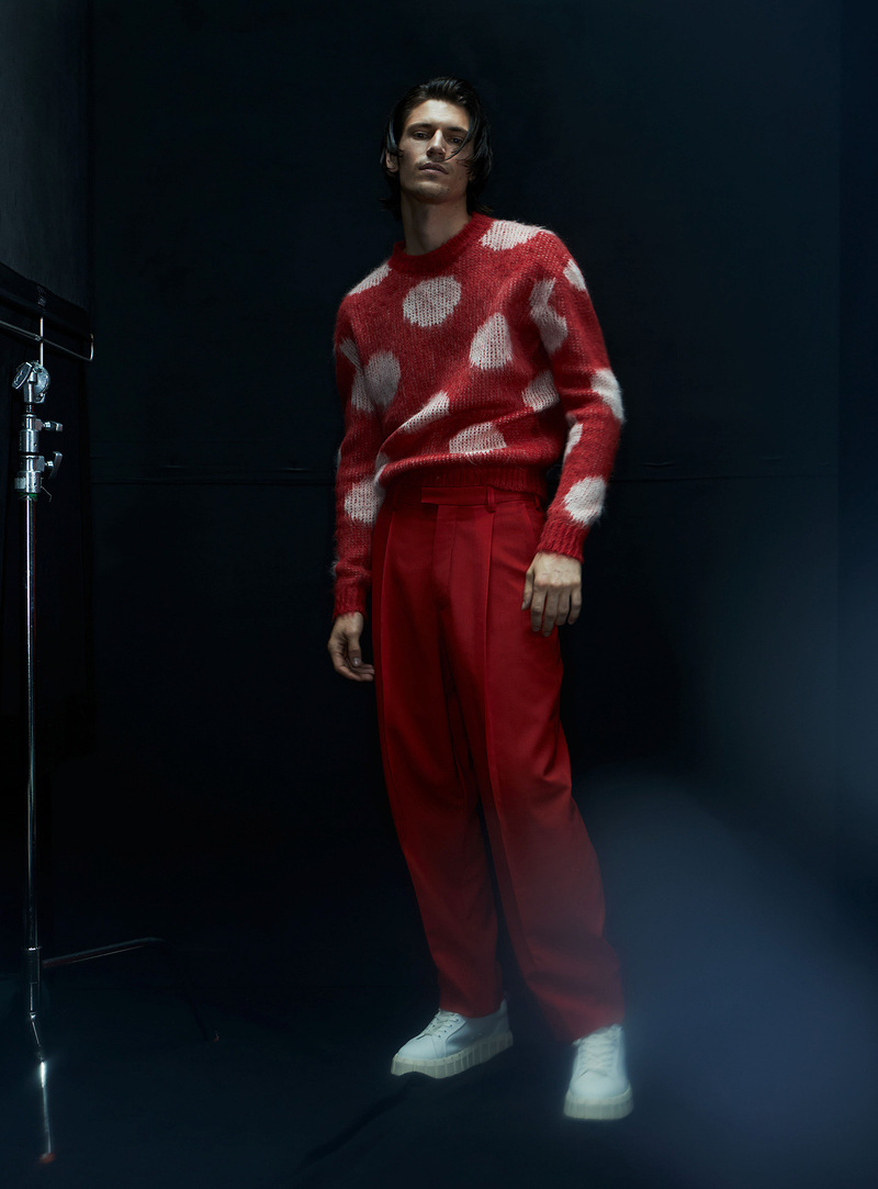 Dressed in a red and white polka dot sweater with pleated trousers, Justin Eric Martin wears Marni.