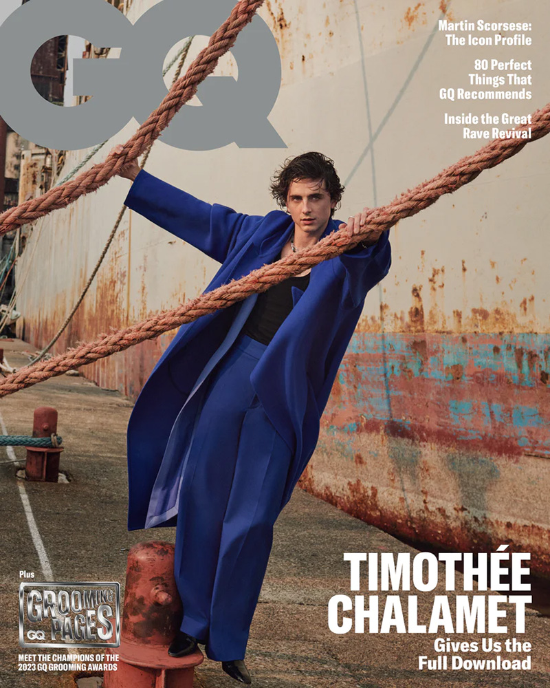 Timothée Chalamet channels maritime chic on the GQ cover for 2023, striking a pose with a bold blue Valentino Haute Couture coat against a rustic ship backdrop.