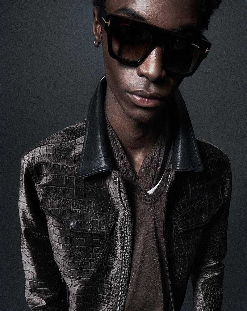 Sleek in black, Ahmed Richards exudes cool sophistication in a croc-effect leather jacket with classic Tom Ford sunglasses.