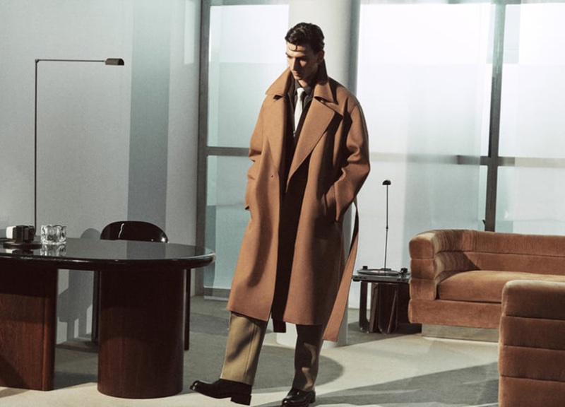 Capturing a moment of contemplation, Thibaud Charon showcases a sleek beige overcoat by Zara Edition.
