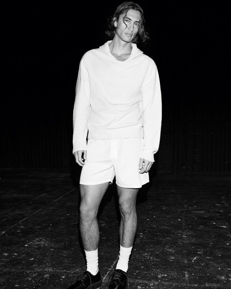 Model James Turlington wears a monochromatic ensemble, sporting a white hoodie.