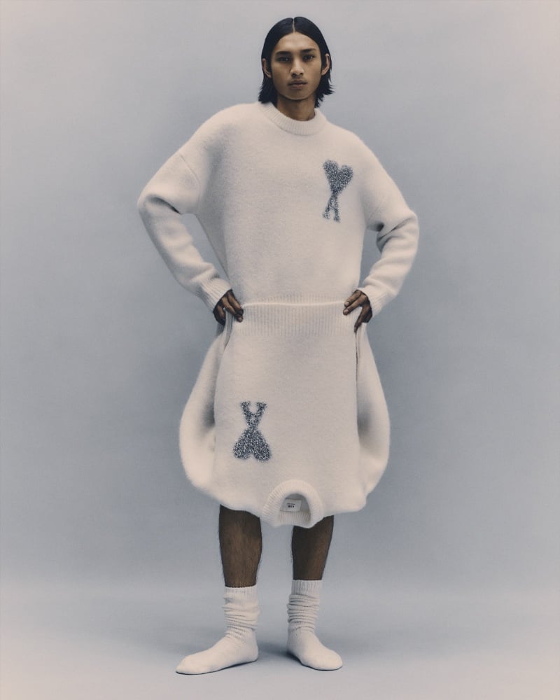 Model Ridzman Zidaine wears an oversized white sweater adorned with an AMI logo.