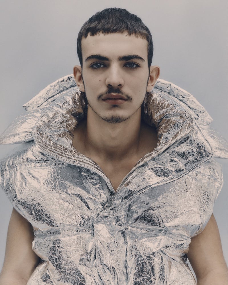 Amine Lakhal models a metallic silver AMI vest with textured, oversized shoulders. 