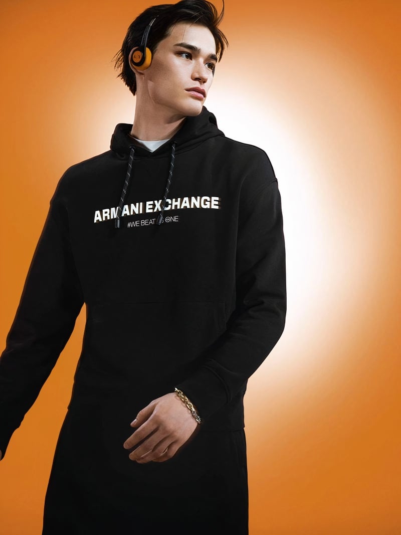 Alex Schlab cuts a sporty figure in a black hoodie emblazoned with the Armani Exchange logo for the brand's fall-winter 2023 campaign.
