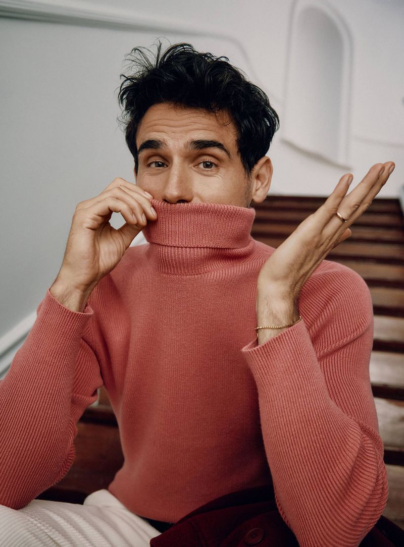 Top model Arthur Kulkov strikes a playful pose in a coral turtleneck. 