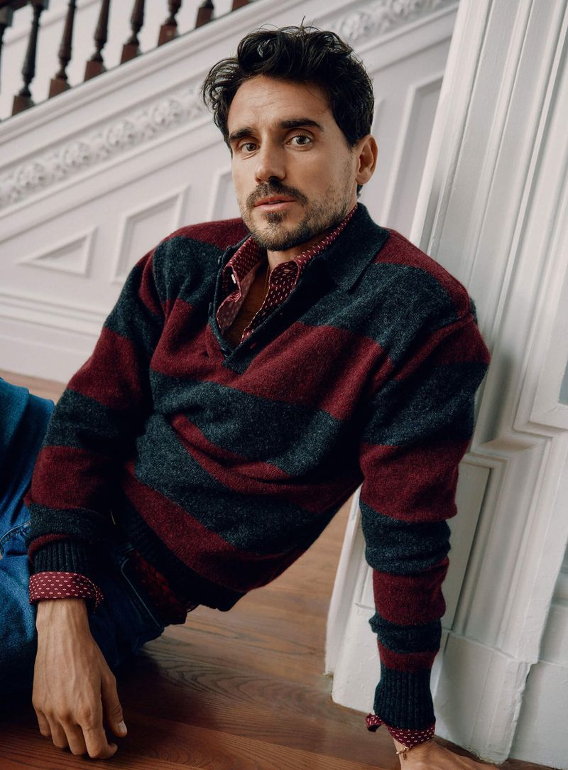 Arthur Kulkov dons a striped polo sweater and patterned shirt from Simons. 