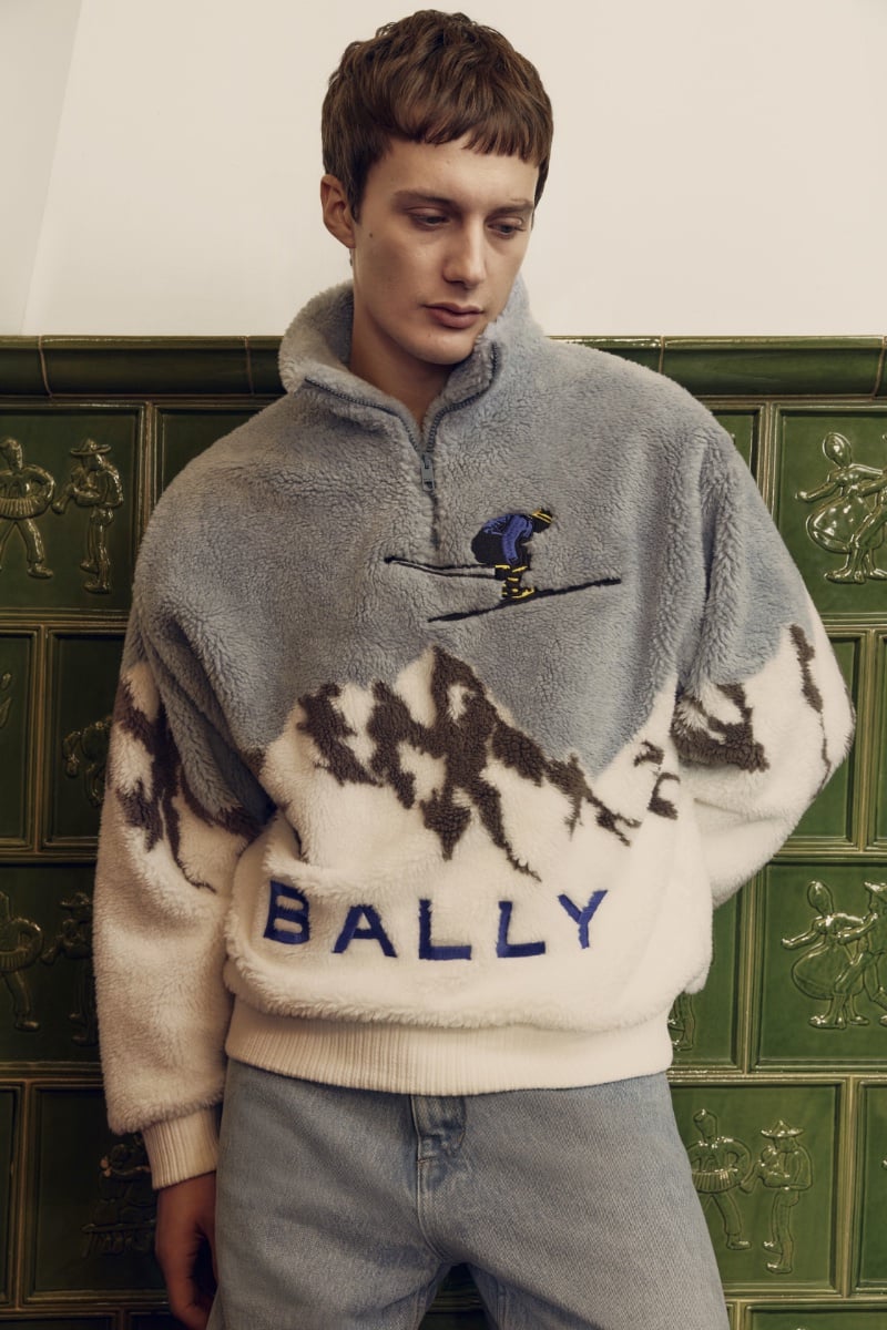 Model Gabriele Gratti pairs comfort with luxury, wearing a fleece Bally pullover with mountain and skier embroidery, complemented by light denim.