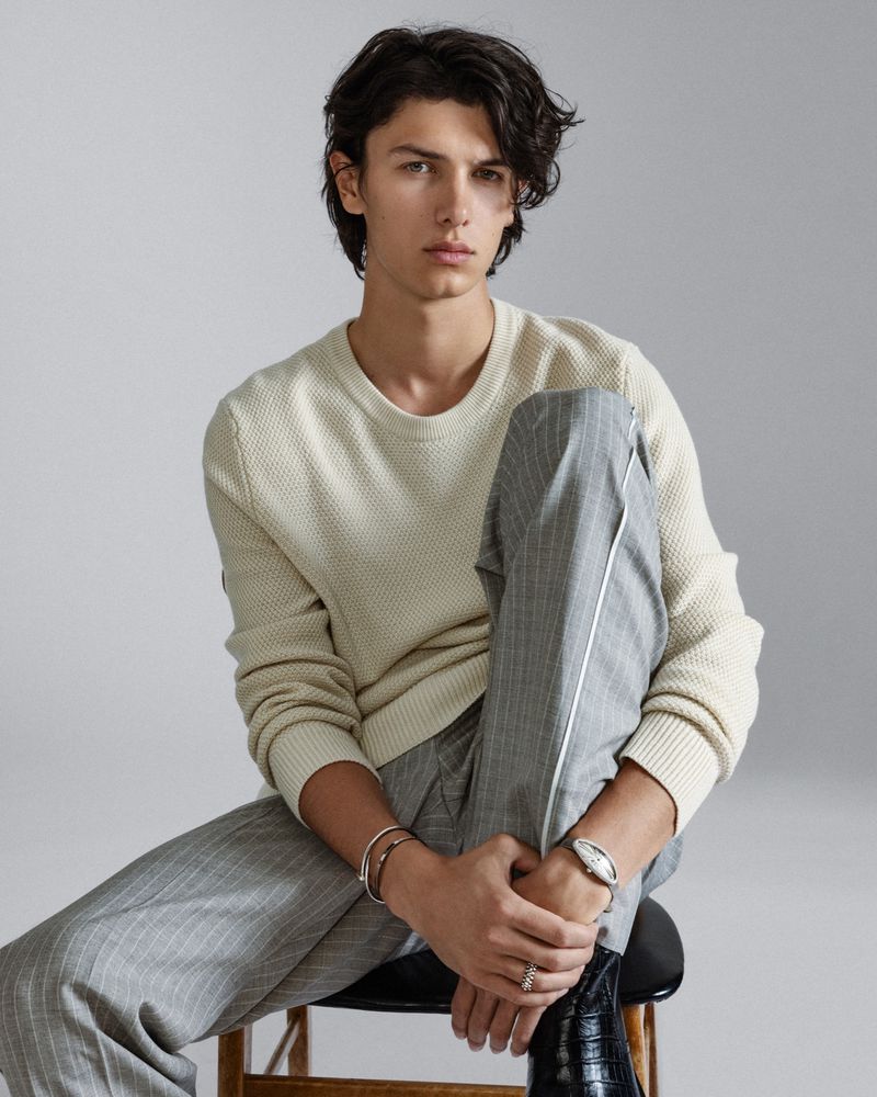 Count Nikolai of Monpezat captures a relaxed yet refined aura in a cream waffle-knit sweater and tailored grey trousers, complemented by sleek Cartier jewelry.