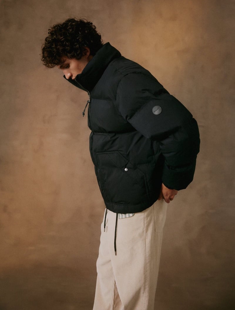 Francisco Henriques showcases winter style in GANT's black puffer jacket and cream corduroy trousers.