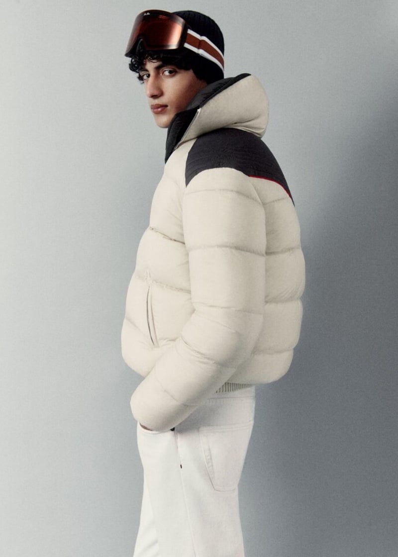 Model Yoesry Detre channels alpine chic in a white puffer jacket paired with a beanie and ski goggles by Loro Piana.
