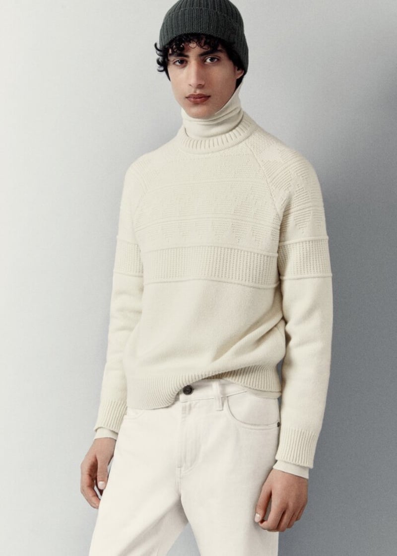 Yoesry Detre exudes quiet elegance in a cream ribbed sweater, turtleneck, and jeans, accented with a dark knit beanie from Loro Piana.