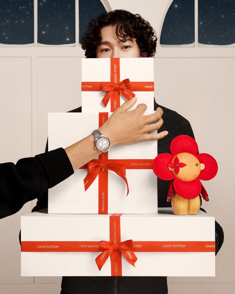 Mathieu Simoneau offers a glimpse of holiday mystery, his eyes peeking over a stack of Louis Vuitton gifts tied with vibrant red ribbons.