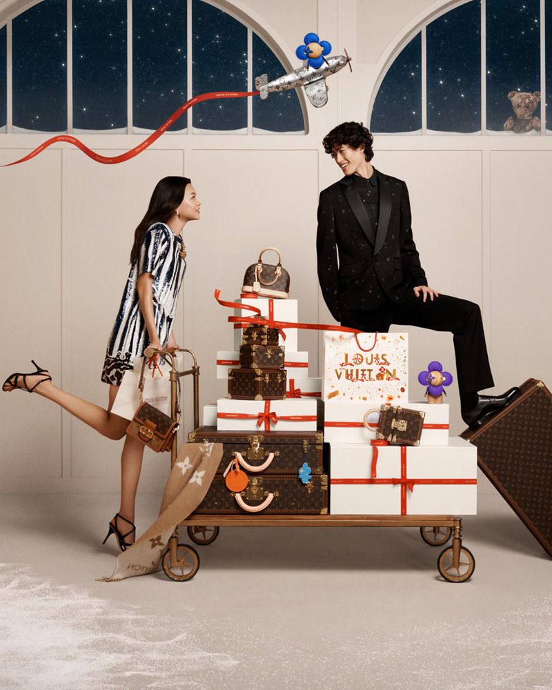 Mika Schneider and Mathieu Simoneau share a moment of festive cheer, surrounded by a treasure trove of Louis Vuitton gifts for the brand's holiday 2023 campaign.