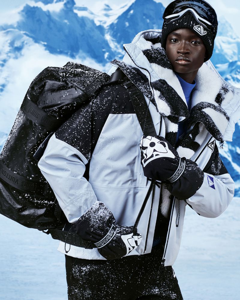 Ahmadou Gueye cuts a striking figure in a snow-speckled Louis Vuitton winter jacket, bringing an air of rugged elegance to the alpine setting.