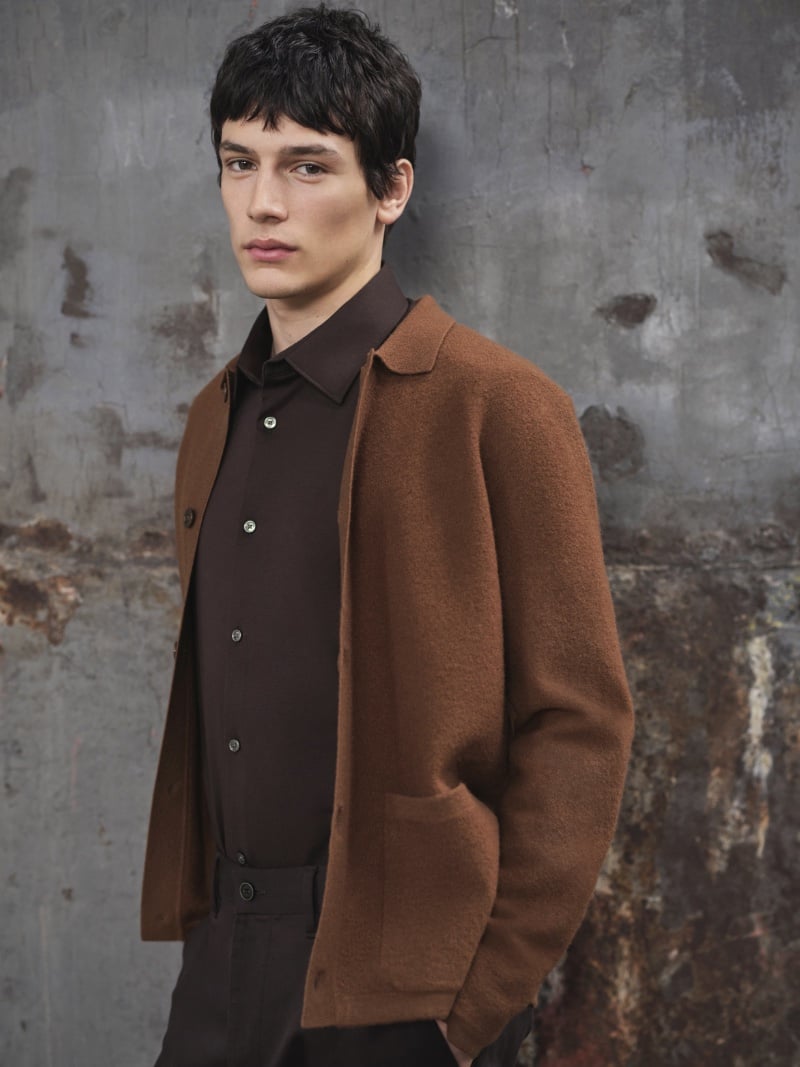Filipe Neves embraces a minimalist aesthetic, donning a brown knit jacket over a dark shirt for the M&S fall-winter 2023 campaign.