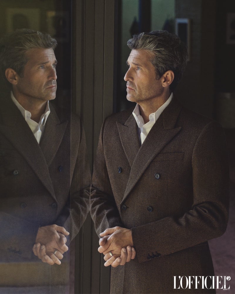 His image mirrored against the glass, Patrick Dempsey is clad in a textured brown coat that speaks to timeless elegance. 