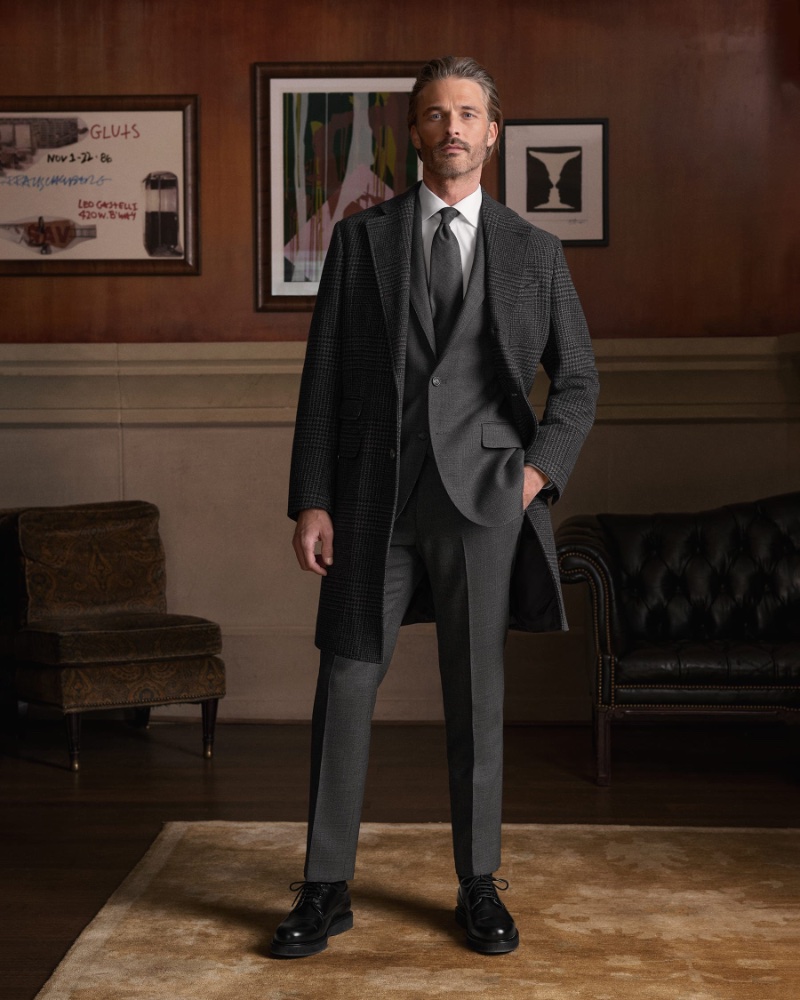 Ben Hill models Proper Cloth's winter 2023 collection, featuring a sleek charcoal suit, paired with a classic overcoat.