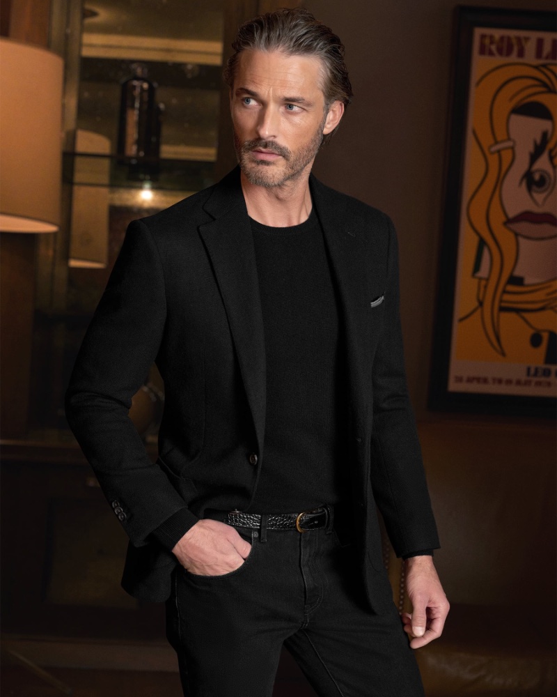 Donning a tailored black ensemble, Ben Hill epitomizes sleek sophistication for Proper Cloth's winter 2023 collection.
