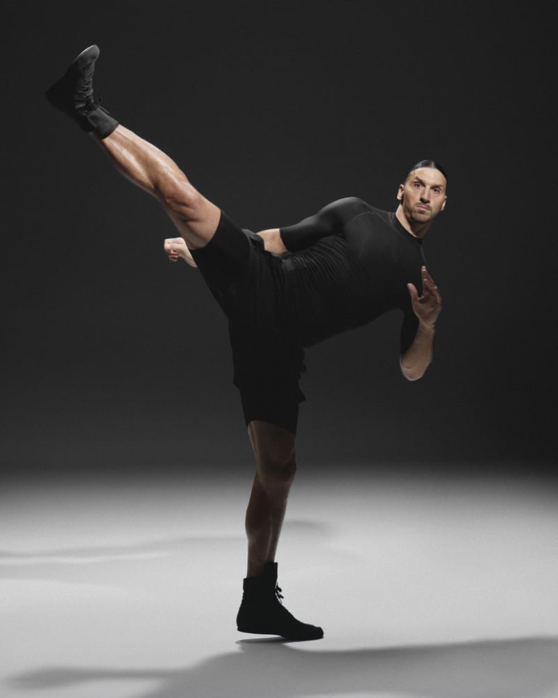 Zlatan Ibrahimović demonstrates his iconic flexibility in a dynamic high kick pose, dressed in a sleek black athletic H&M Move outfit.