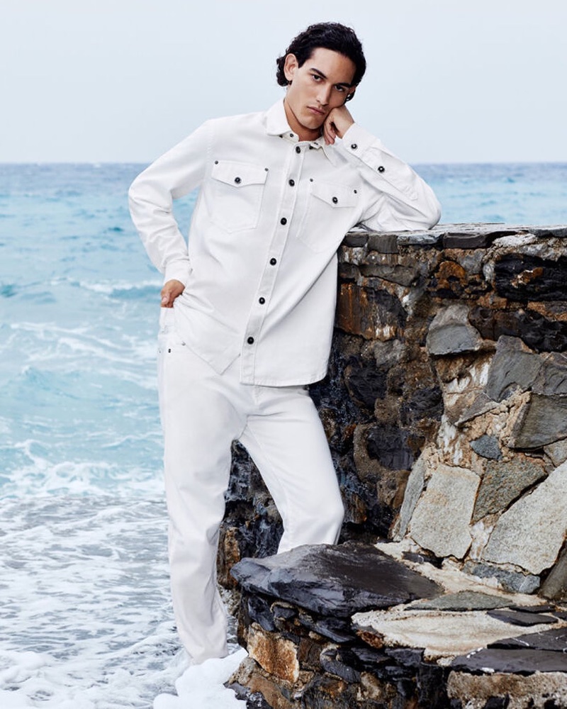 Antonio Guitto models an all-white outfit for Versace's resort 2024 campaign.
