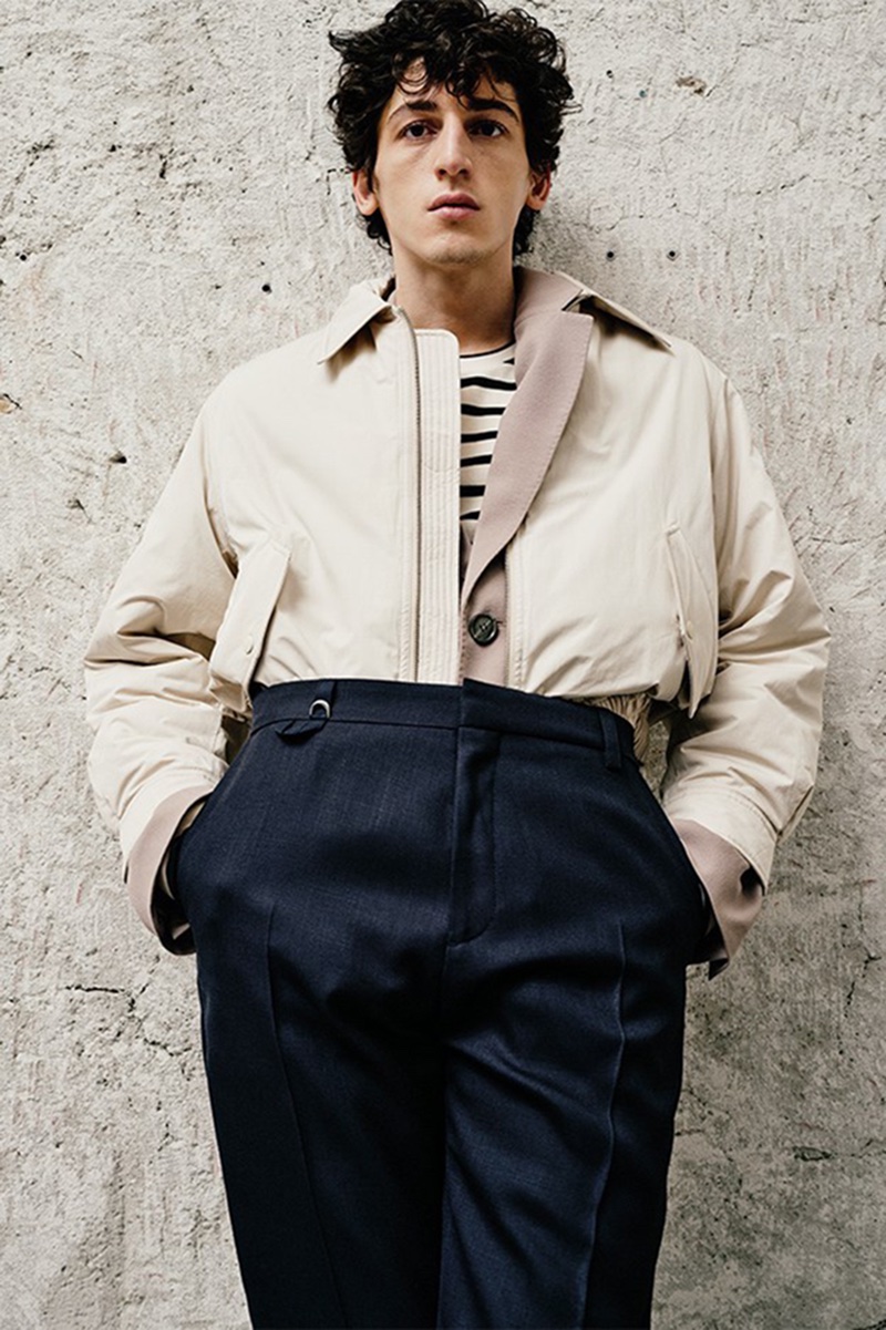 Aslan Tsallatii models a Dunst bomber jacket over an AMI blazer and Jil Sander striped t-shirt, finished with JACQUEMUS trousers for LuisaViaRoma.