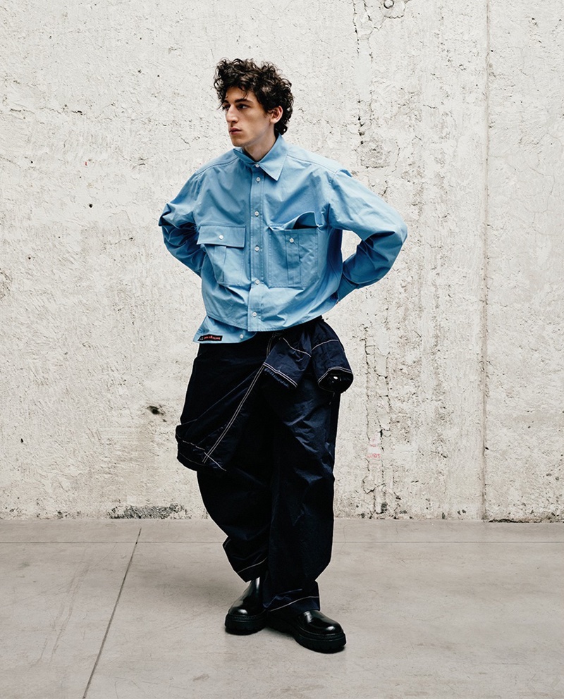Aslan Tsallatii showcases a Bottega Veneta ensemble featuring a hooded jacket, double-layer shirt, nylon pants, and leather boots for LuisaViaRoma.