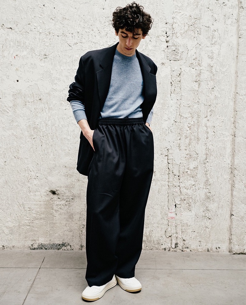 LuisaViaRoma highlights Aslan Tsallatii in Acne Studios: a sleek blazer, cozy sweater, tailored pants, and casual sneakers.