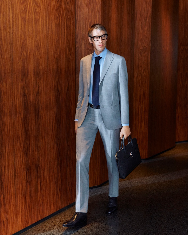 A vision in gray, Joel Frampton wears a Kiton suit with Prada glasses and a Thom Browne briefcase for Mytheresa.