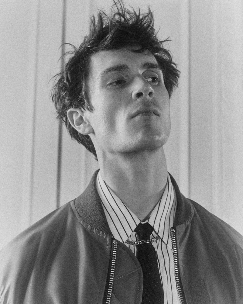 Captured for Mr Porter, William Bracewell layers a Sacai bomber jacket over a Bottega Veneta striped shirt, paired with a Saint Laurent tie and a Tom Wood chain necklace.