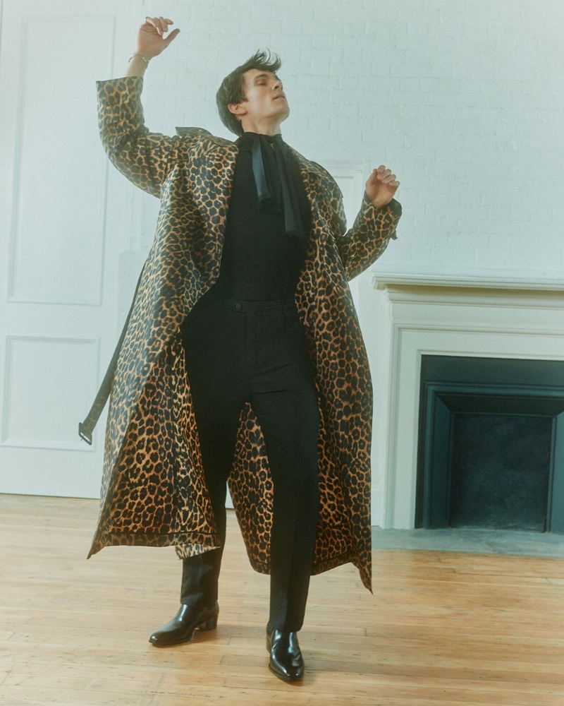 William Bracewell models a Saint Laurent leopard print trench coat paired with a crisp polo shirt, sleek tuxedo trousers, Chelsea boots, and a silk scarf for Mr Porter.