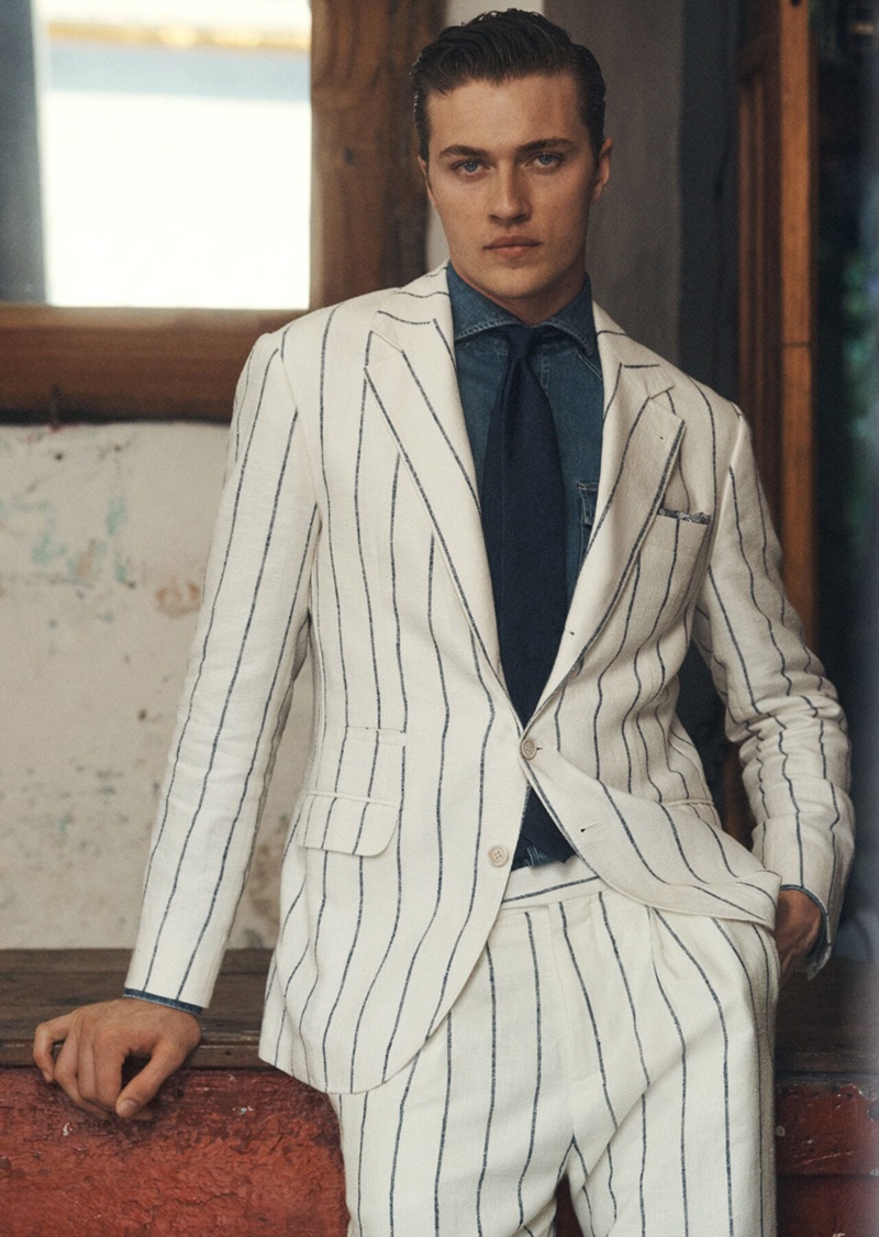 Lucky Blue Smith wears a white linen pinstripe suit with a denim shirt for Brunello Cucinelli's spring-summer 2024 campaign.
