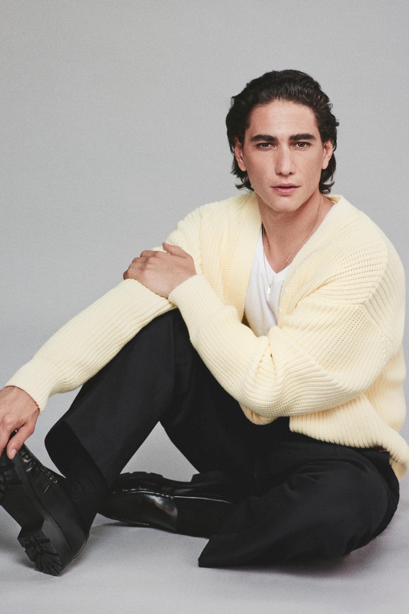 Enzo Vogrincic charms in a soft, pale yellow cardigan from Zara.