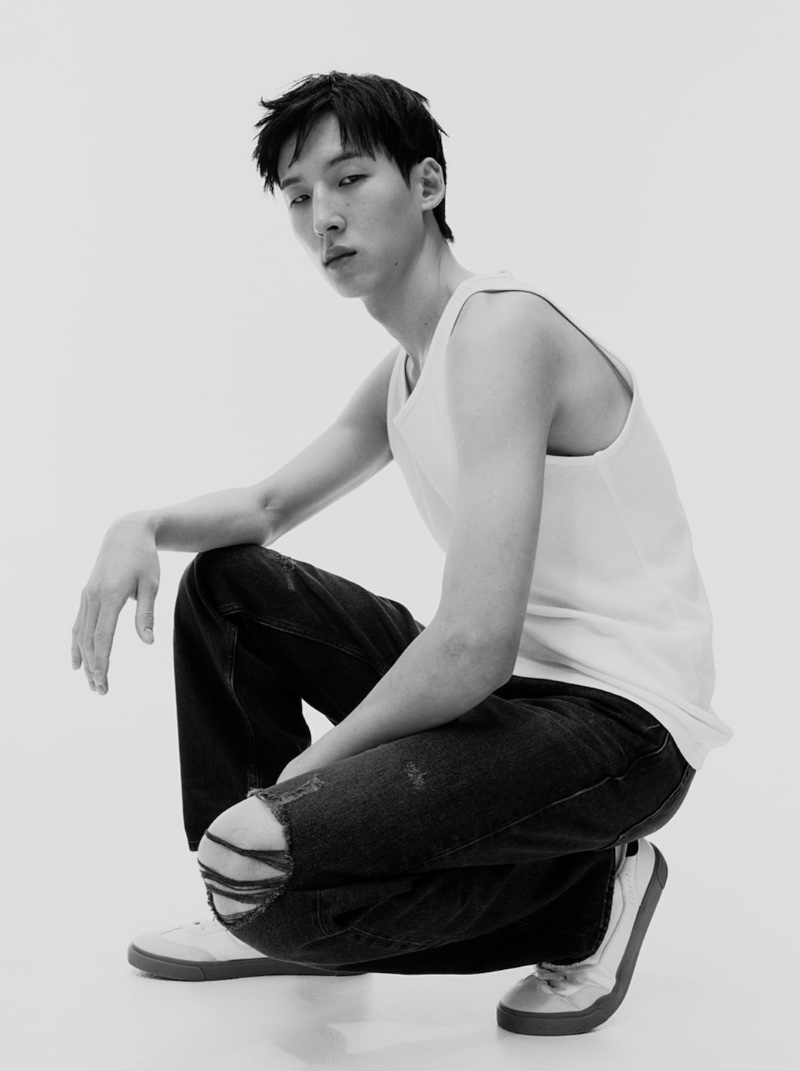 Woosang Kim exudes effortless cool in loose-fit jeans and a sleeveless white tank top.
