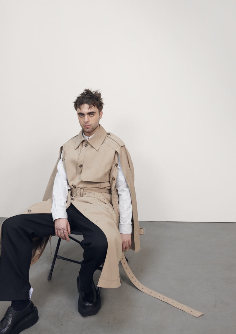 Seated, Lennon Gallagher models a deconstructed trench from the H&M x Rokh collection.