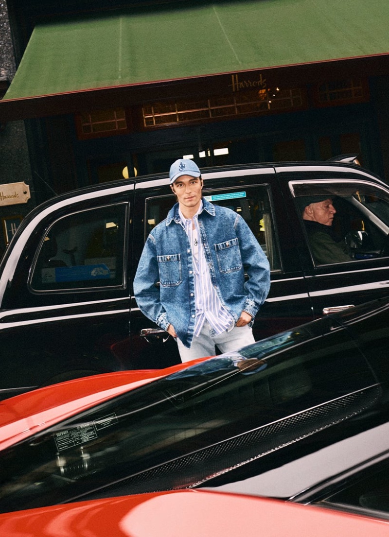 Francesco Mariottini poses outside Harrods, donning a Hed Mayner denim jacket, JW Anderson cap, and EZR jeans.