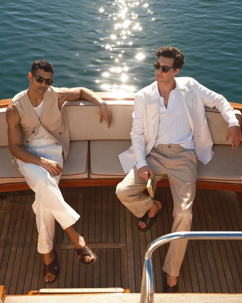 Left: Jonas Barros wears a cotton utility vest with relaxed-fit chinos, a mesh tank, and leather woven crisscross sandals. Right: Adam Sattrup models an Italian double-breasted tuxedo jacket with relaxed-fit chinos and Nomad suede leather crossover sandals. 