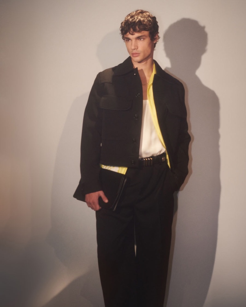Fernando Lindez fronts Versace's spring-summer 2024 campaign, clad in a black jacket and trousers with a vibrant yellow shirt.