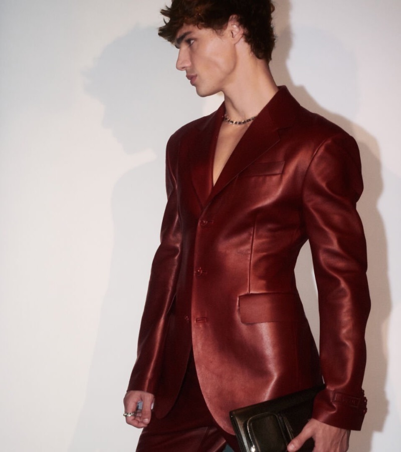 Model Fernando Lindez exudes confidence in a sleek, oxblood leather suit for Versace's spring-summer 2024 ad.