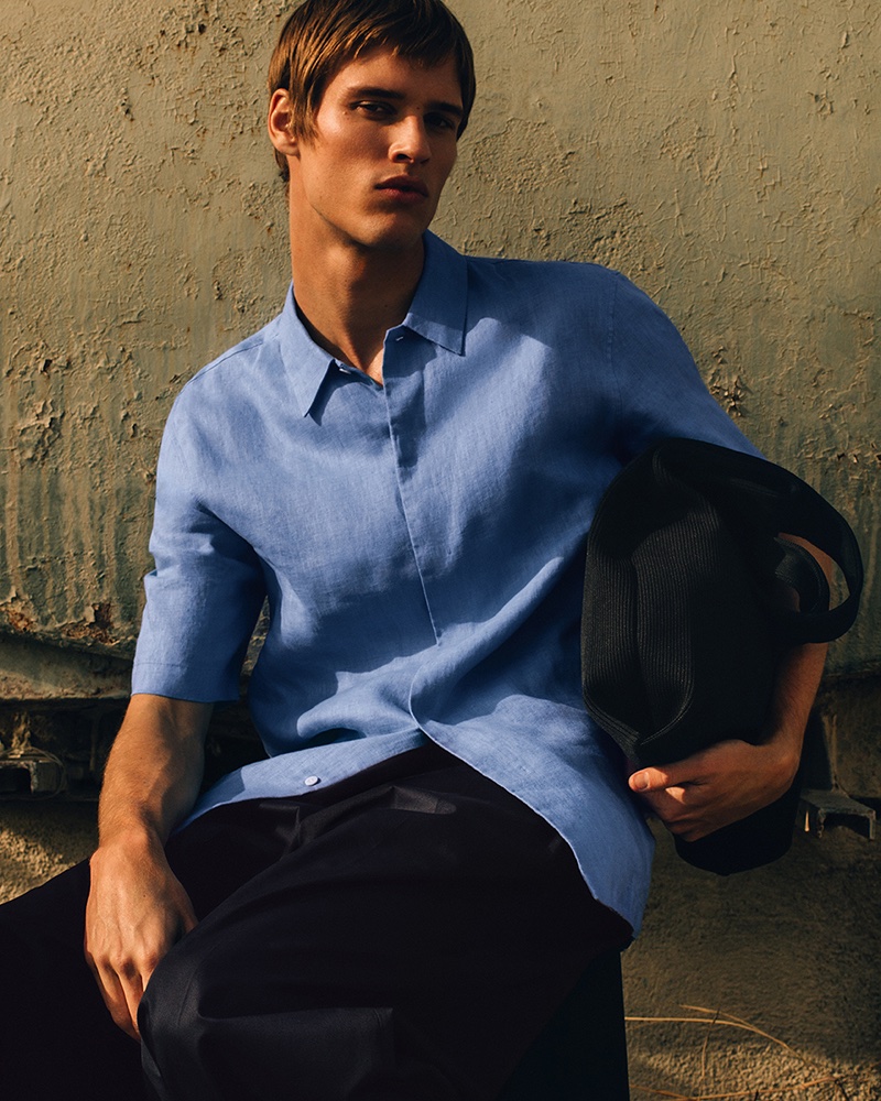 Model Yeray Allgayer dons a blue linen shirt and dark trousers from COS' summer 2024 collection.