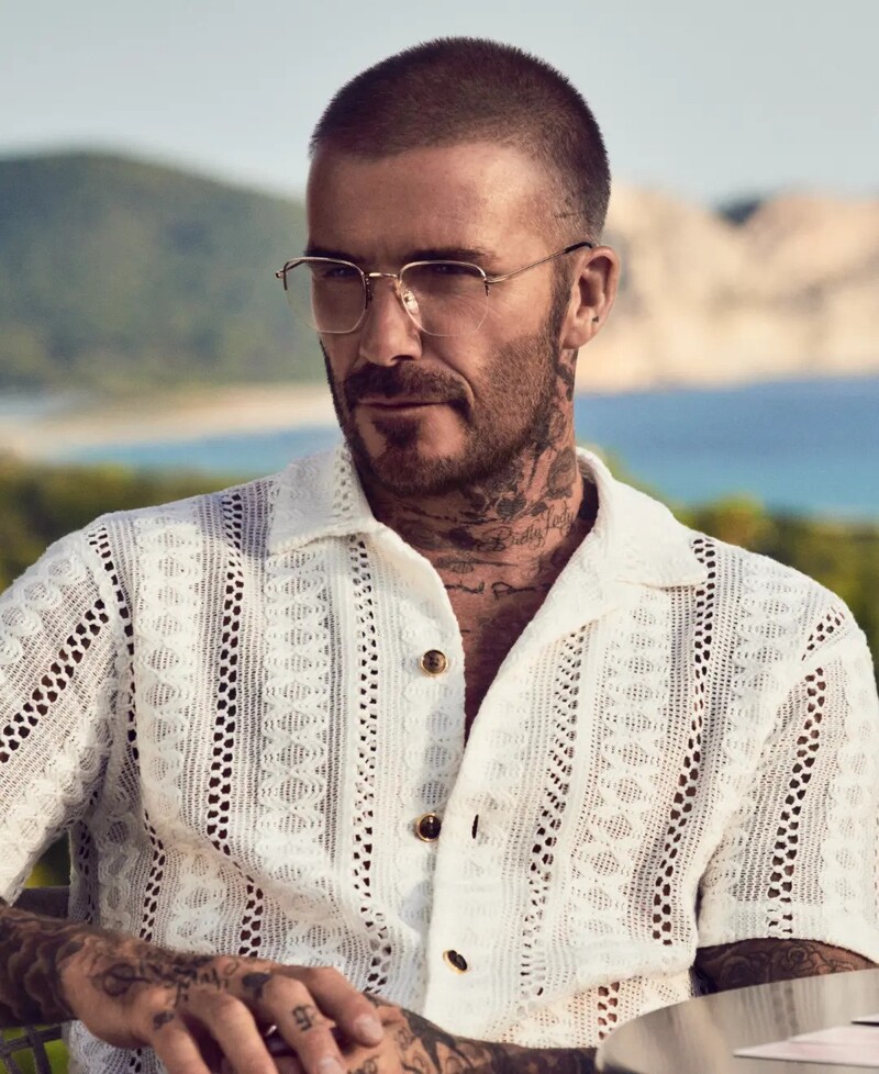 David Beckham pairs a crochet short-sleeve shirt with oversized glasses for his spring 2024 eyewear advertisement. 