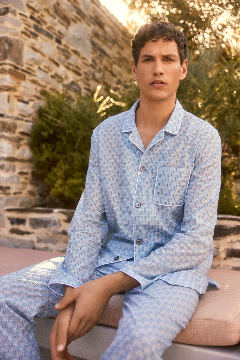 Model Paul Hupfer lounges in blue pajamas from Derek Rose's spring-summer 2024 collection.