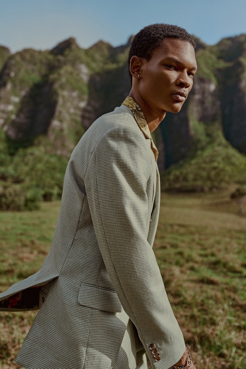 Jabali Sandiford strikes a powerful pose in a houndstooth jacket, epitomizing the Indochino spring-summer 2024 campaign's elegance against a mountainous backdrop.